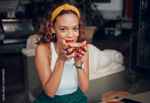 Black woman, coffee and smile for relax at cafe in joyful happiness, carefree and thinking in shop. Portrait of happy African American female enjoying a warm drink at a indoor restaurant photo