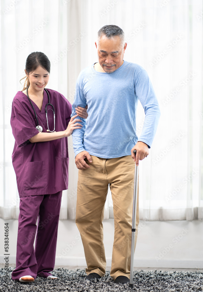 Beautiful nurse helps senior man patient in hospital holding stick ...