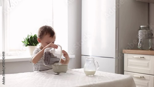 a cute little boy pours chocolate flakes into a bowl. the concept of healthy nutrition.