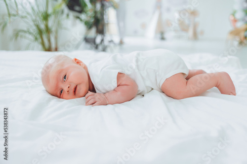 Cute 2-month-old baby lying on the bed, natural bed linen. delicate baby skin.