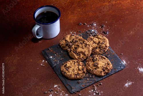 Coffee mug with chocolate cokies photographed on rustic painted background. photo