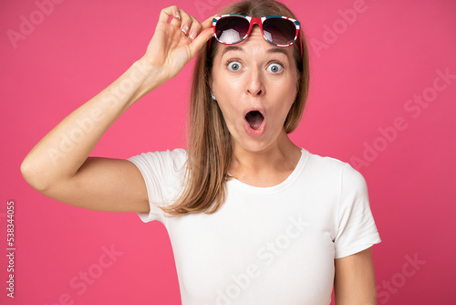 Photos impressed shocked young attractive woman dressed in white t-shirt and holding su