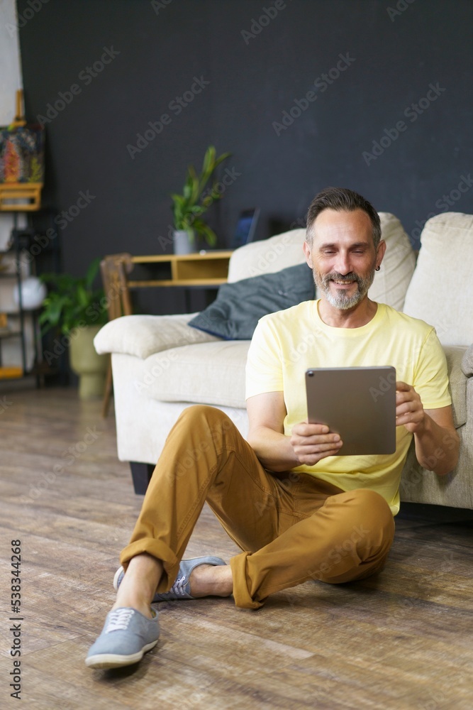 Attractive beard man sitting on the floor with tablet pc doing homework and studying for test for the university. Business man working. Business, education, lifestyle