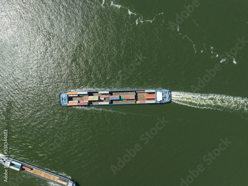 Top down view of an inland transportation vessel for container shipping and logistics distribution. Ship loaded with containers and merchandise for commercial and international transport. Aerial photo