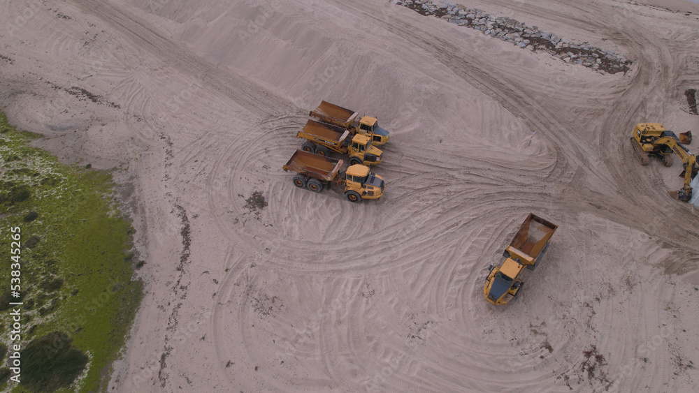 Esposende, Portugal, April 10, 2022: Aerial view of the two sides of Restinga de Ofir. Esposende fishing harbor maintenance dredging. Dumper vehicles and rotating excavator parked on the sand.