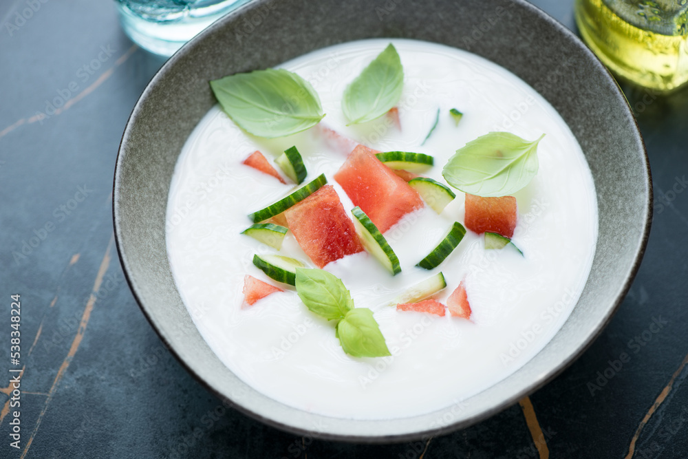 Bowl of cold summer soup with buttermilk, watermelon and cucumber, horizontal shot on a dark-olive marble background, middle closeup Bowl of cold summer soup with buttermilk, watermelon and cucumber, horizontal shot on a dark-olive marble background, middle closeup