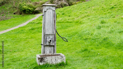 Old wooden hand operated water pump and stone trough