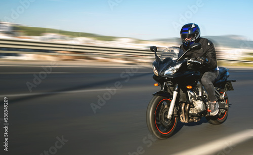 Side view of a motorcycle rider riding on the highway road with motion blur.
