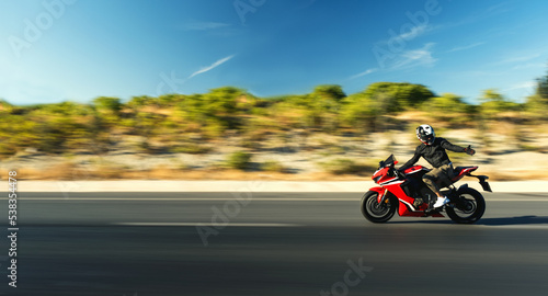 Side view of a motorcycle rider riding red race motorcycle on the highway with motion blur.