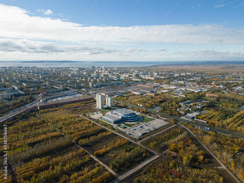 Aerial panorama of the city on the riverbank. A river near the city in the warm light of sunrise. Bird's-eye view. Aerial photography. A picture from a drone.