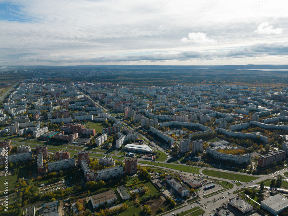 Obraz premium Aerial panorama of the city on the riverbank. A river near the city in the warm light of sunrise. Bird's-eye view. Aerial photography. A picture from a drone.