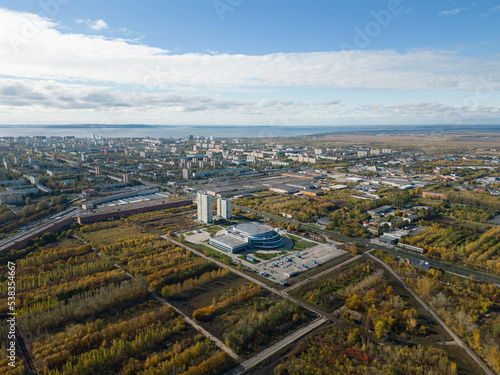 Aerial panorama of the city on the riverbank. A river near the city in the warm light of sunrise. Bird's-eye view. Aerial photography. A picture from a drone.
