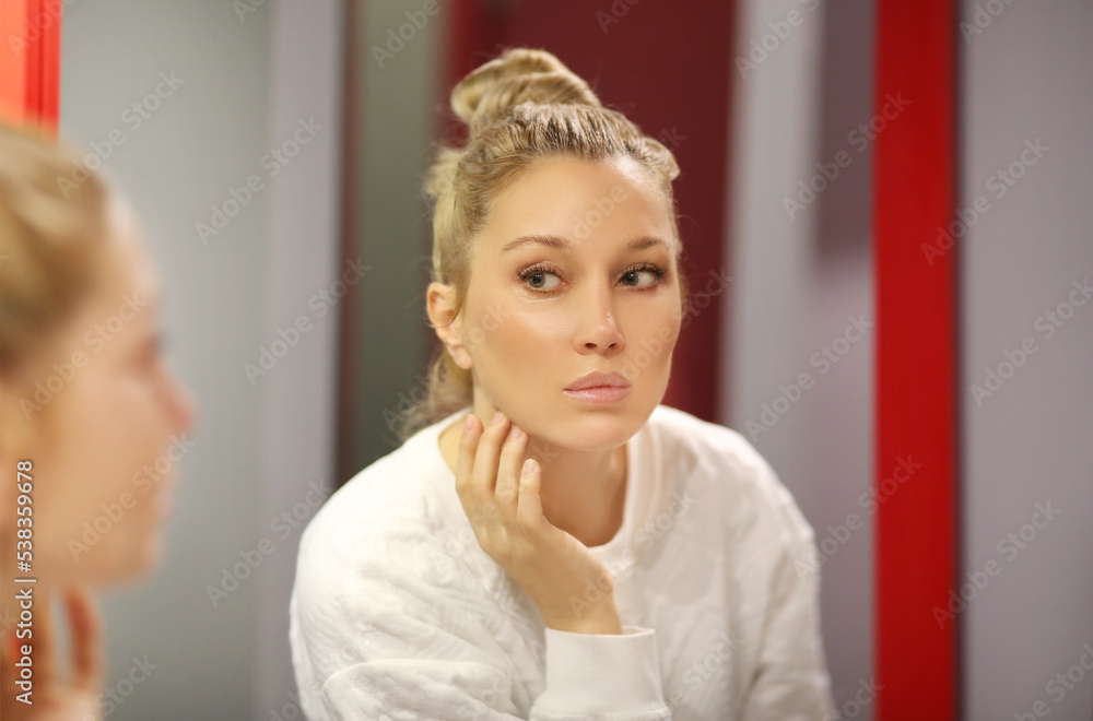 woman looking in the mirror in the bathroom and taking care of her skin. woman looking in the mirror in the bathroom and taking care of her skin.
