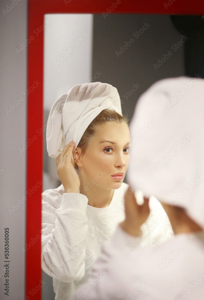 woman looking in the mirror in the bathroom and taking care of her skin. woman looking in the mirror in the bathroom and taking care of her skin.