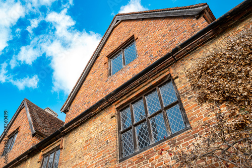 Dramatic view of an old, Tudor-built house showing the fine brickwork, leaded windows and apex roof.  Part of English heritage. photo