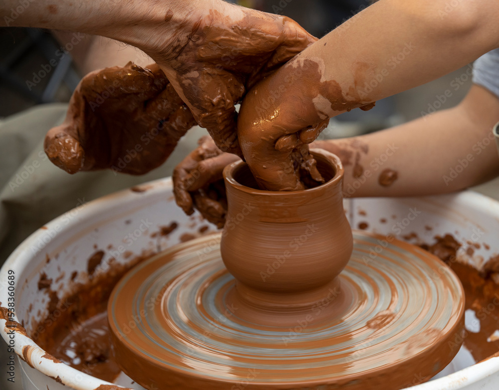 The potter teaches a young student. Hands of a potter