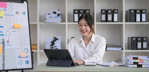 Asian Businesswoman Using laptop computer and working at office with calculator document on desk, doing planning analyzing the financial report, business plan investment, finance analysis concept. © wichayada