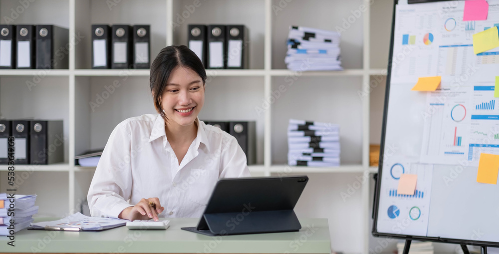 Asian Businesswoman Using laptop computer and working at office with calculator document on desk, doing planning analyzing the financial report, business plan investment, finance analysis concept. Asian Businesswoman Using laptop computer and working at office with calculator document on desk, doing planning analyzing the financial report, business plan investment, finance analysis concept.