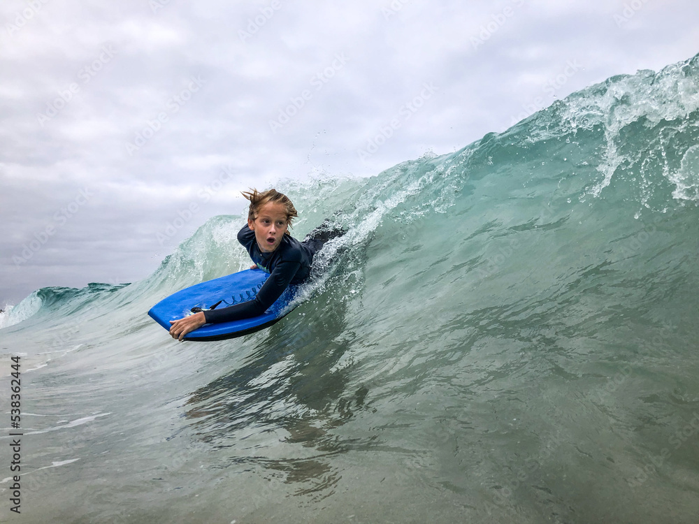 Male youth surfing wave on boogie board in ocean Male youth surfing wave on boogie board in ocean