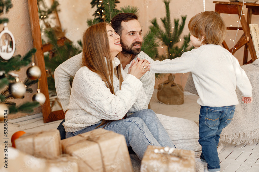 Mother, father and their son sitting near Christmas tree at home Mother, father and their son sitting near Christmas tree at home