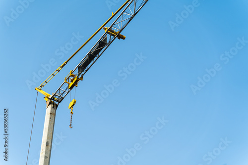 Yellow crane doing work and moving weights. Construction concept. construction and crafts. light blue background. neutral sky.