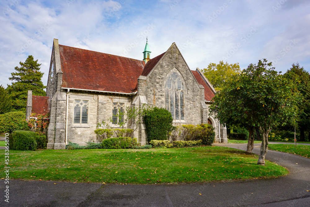 old English church surrounded by greenery. traditional stone chapel in city cemetery 