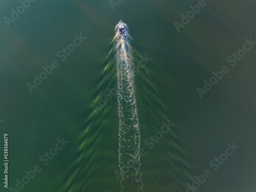 Aerial view of a small boat creating a wake in a wide river