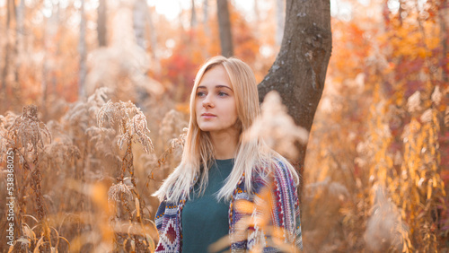 Portrait of young blonde woman in autumn forest.