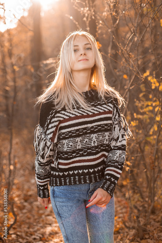 Young blonde woman walking outdoors under sunlight in autumn