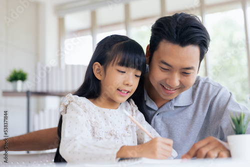 Attractive asian father teaching little child daughter learning studying doing homework at home, Family quality time and e-learning education concept