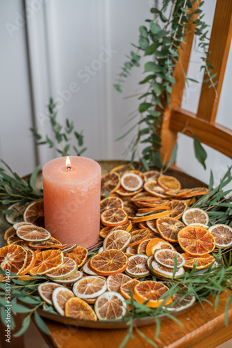Adventsschale mit Kerze, Eukalyptus und getrockneten Orangenscheiben auf goldenem Teller dekoriert für Weihnachten, minimalistische Dekoration 