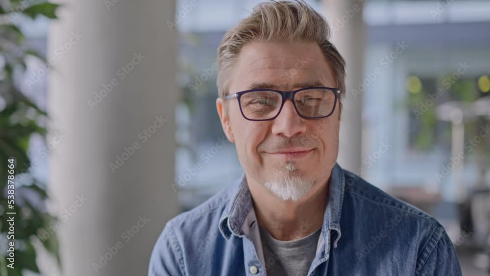 Portrait of happy middle aged man in glasses, standing in office lobby wearing casual shirt. Portrait of happy middle aged man in glasses, standing in office lobby wearing casual shirt.