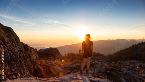 Adventurous Woman Hiker on top of Canadian Mountain Landscape. Sunny Sunset Sky. Top of Mt Seymour near Vancouver, British Columbia, Canada. Adventure Travel Concept © edb3_16