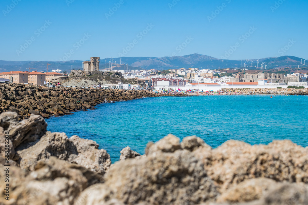 Intentional blurred stones with wall that connects Las Palomas island to Tarifa and is border between the Atlantic Ocean and the Mediterranean Sea with landmarks in the background, Tarifa SPAIN
