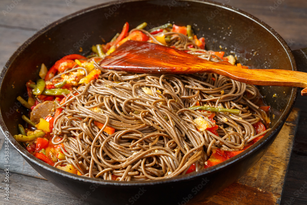 Soba with vegetables in soy sauce and teriyaki in a frying pan hot coarse. Soba with vegetables in soy sauce and teriyaki in a frying pan hot coarse.