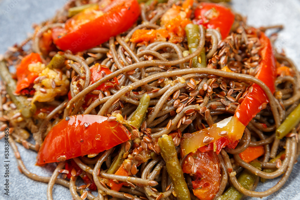 Soba with vegetables in soy sauce with spices in a plate close-up. Soba with vegetables in soy sauce with spices in a plate close-up.