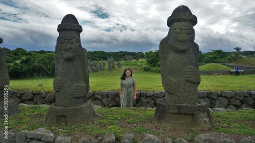 Mujer posa frente a estatuas de roca en la isla de Jeju, Corea del Sur