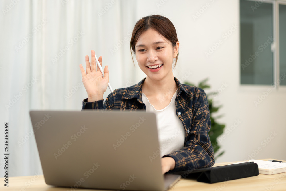 Teenage girl is using laptop to video conference and make greeting gesture with classmates and lecturer Teenage girl is using laptop to video conference and make greeting gesture with classmates and lecturer