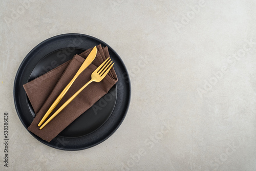 table place setting with black plates and golden cutlery