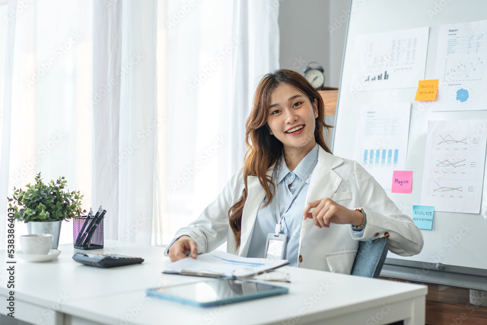 Businesswoman is looking on camera and smiling with confident while sitting to working analysis investment Businesswoman is looking on camera and smiling with confident while sitting to working analysis investment