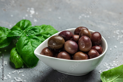 red kalmata olives with fresh rosemary in a small bowl on gray background. Long banner format. top view