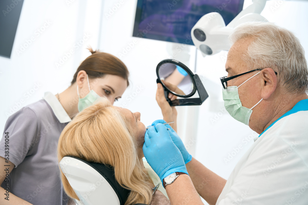 Blonde female patient is getting dental check up in medical center Blonde female patient is getting dental check up in medical center