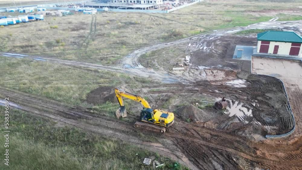 A powerful excavator digs the ground at a construction site. View from above. Drone photography. Earthworks with heavy equipment at the construction site. A powerful excavator digs the ground at a construction site. View from above. Drone photography. Earthworks with heavy equipment at the construction site.
