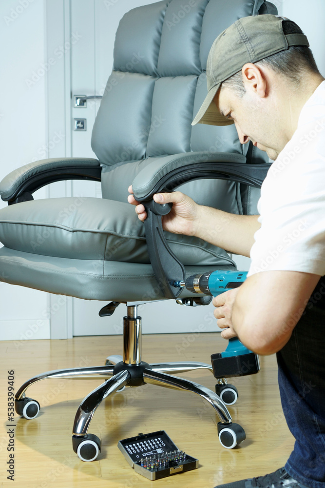 Master repairs office chair with a screwdriver Master repairs office chair with a screwdriver