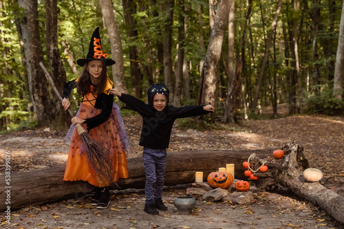 Children wearing witch and bat costumes and having fun in autumn park in Halloween. Happy Halloween. Trick or treat