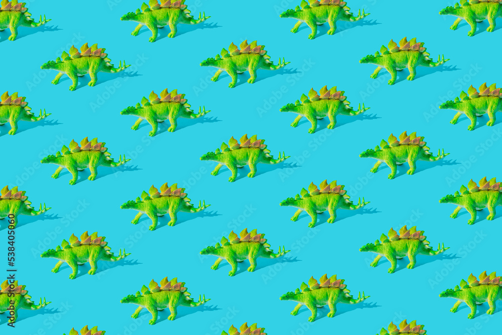 Green Stegosaurus dinosaur toy on a blue background. Pattern.