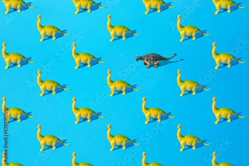 Yellow green Brachiosaurus and gray Ankylosaurus plastic toy dinosaur on a blue background. Pattern.