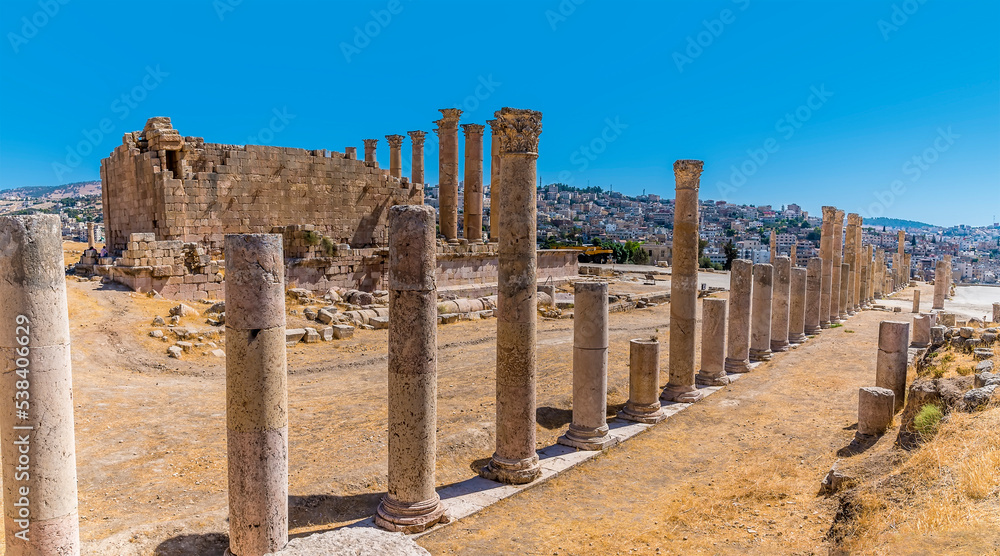 A view along a colonnaded street beside the Temple of Artemis in the ancient Roman settlement of Gerasa in Jerash, Jordan in summertime