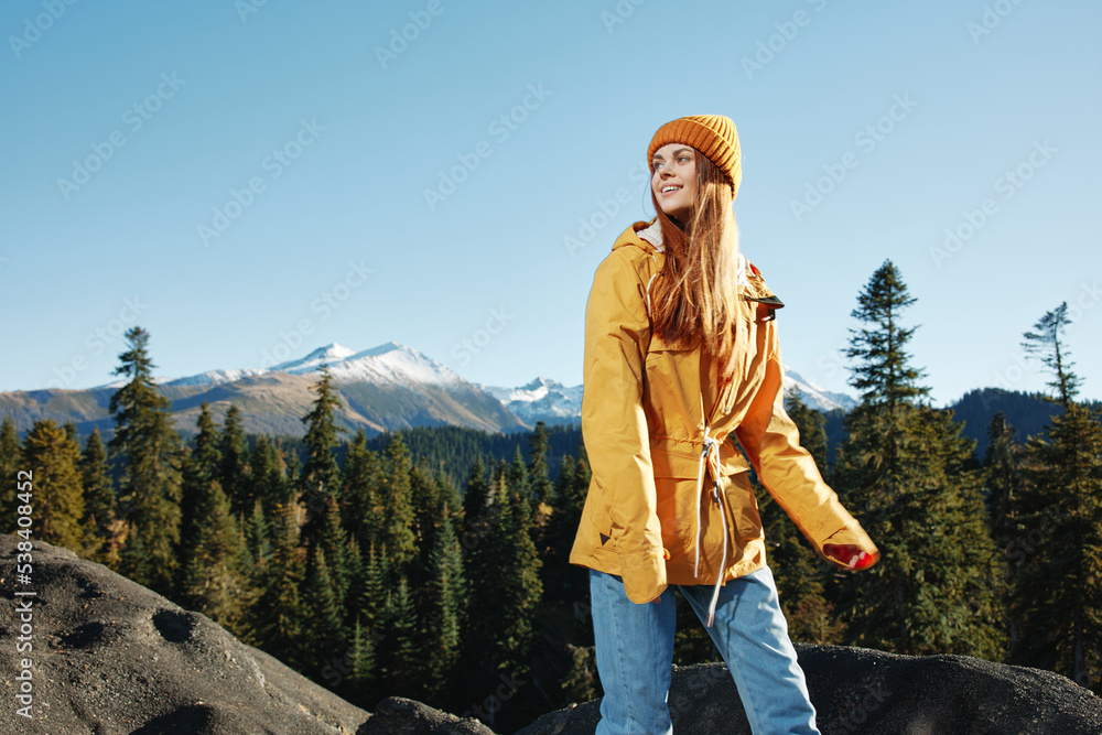 Woman smile with teeth happiness and laughter hiker in yellow raincoat put her hands up and jumping trip in the fall and hiking in the mountains in the sunset freedom