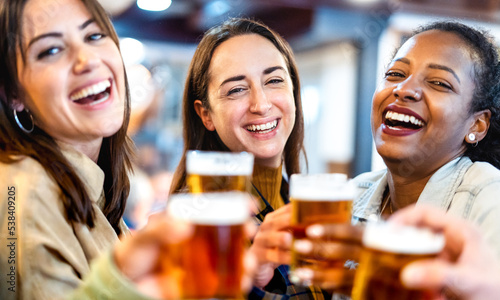 Girlfriends drinking beer at brewery bar restaurant - Lifestyle concept with young women having fun toasting together at pub